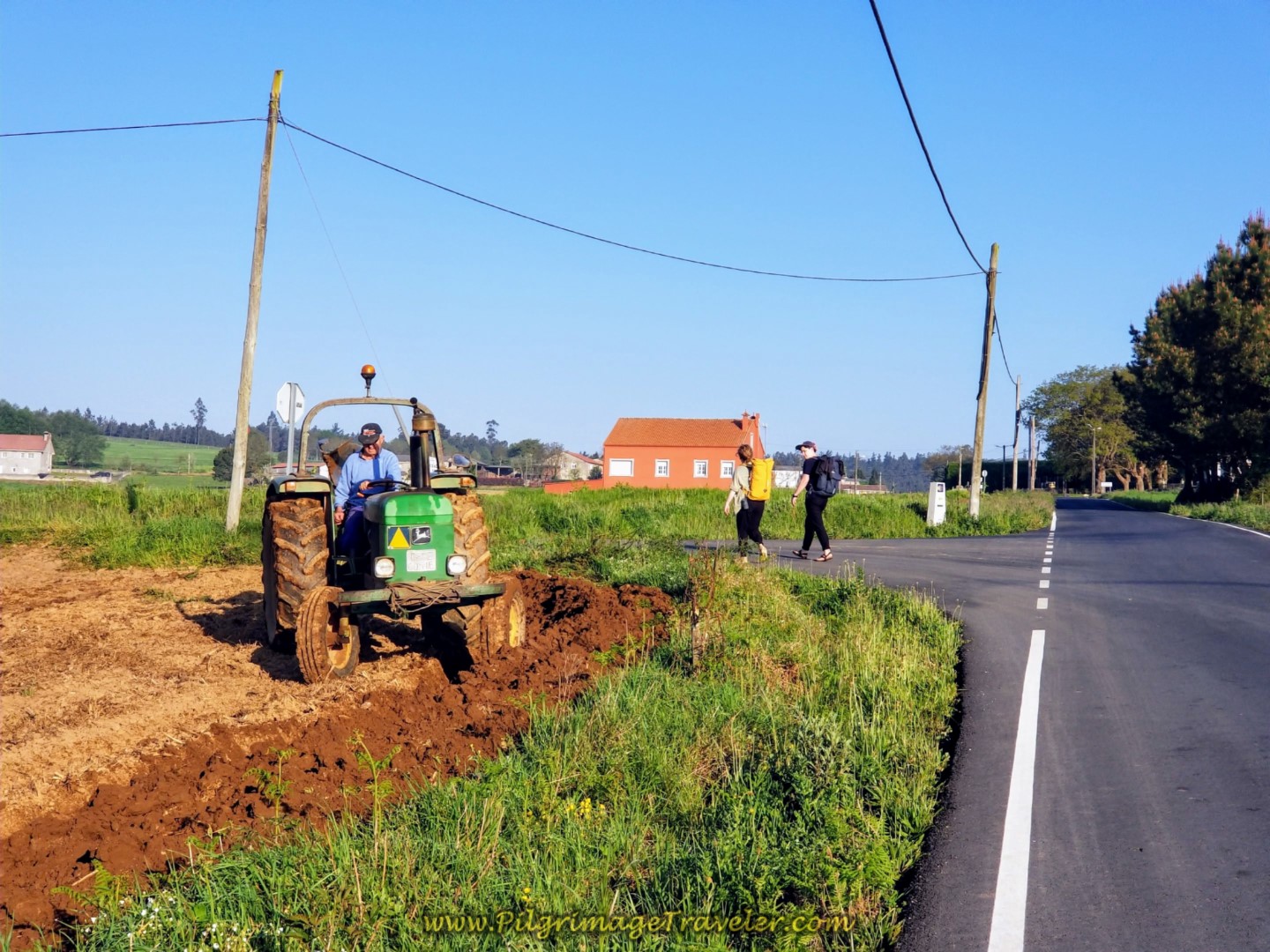 Farmer Plowing as Two Peregrinos Walk By on day eight of the Camino Inglés Farmer Plowing as Two Peregrinos Walk By on day eight of the Camino Inglés