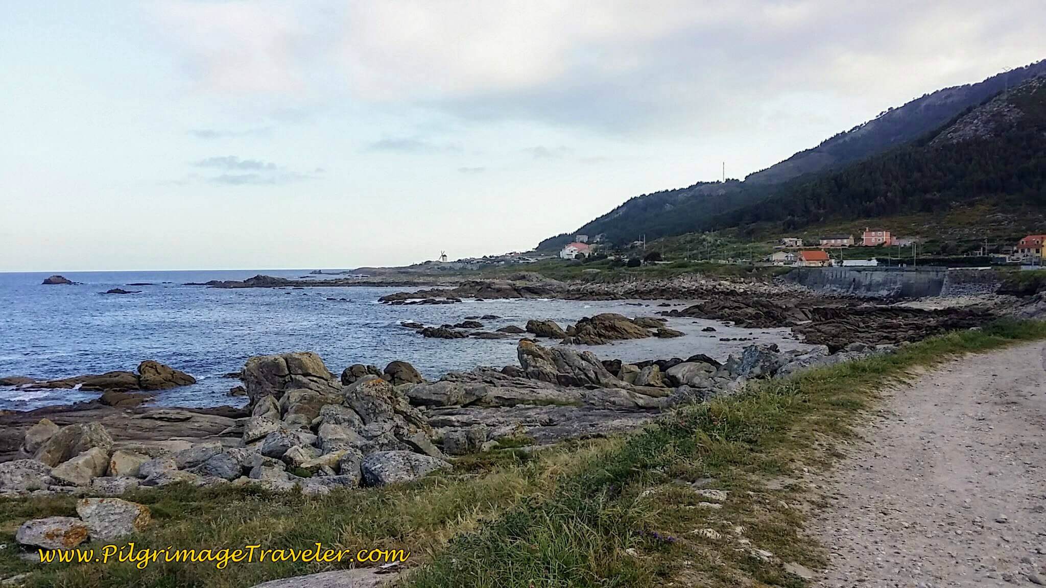 Road along the coastline north of Mougás, toward a prominent windmill on day twenty, Camino Portugués.